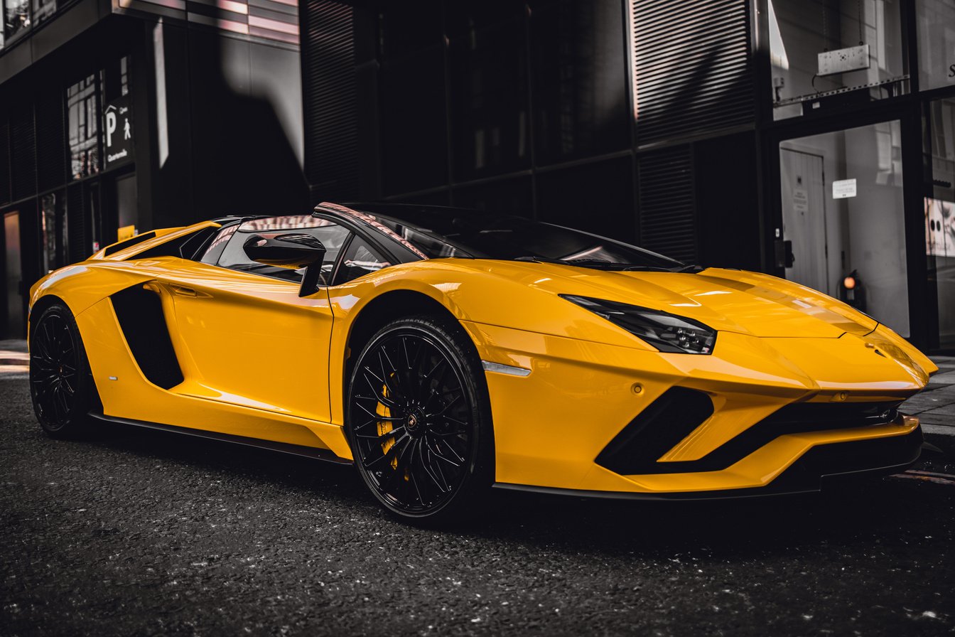 A Yellow Convertible Luxury Car Parked Beside Black Building